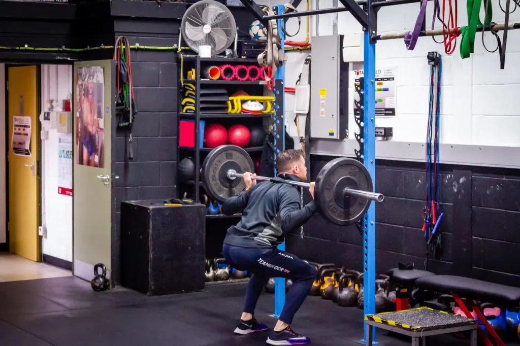 Barbell back squat mid ascent showing strong hip drive and upright torso