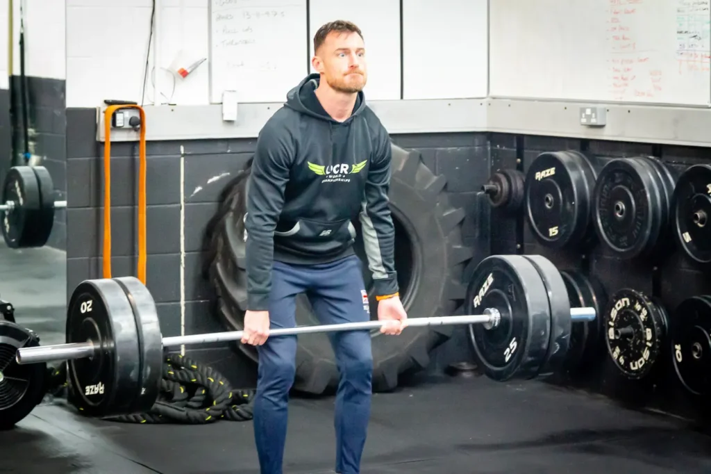Barbell deadlift mid pull position with bar close to legs and neutral spine