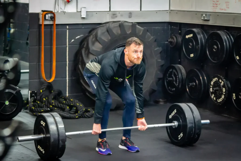 Athlete setting up for a barbell deadlift with hip width stance, bar over mid foot and flat back