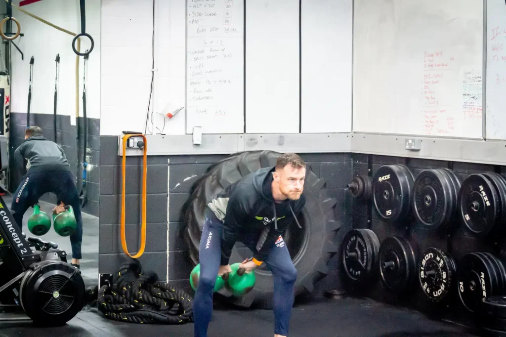 Double kettlebell clean showing explosive hip extension during upward drive