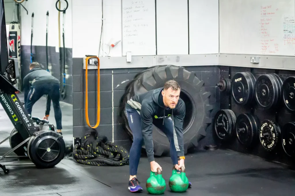 Athlete setting up for a double kettlebell clean with neutral spine and bells between feet