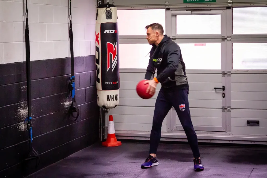 Athlete forcefully throwing a medicine ball into a wall from an open stance