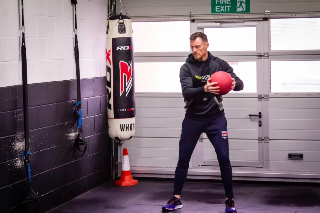 Athlete holding a medicine ball in an open stance preparing for a rotational throw